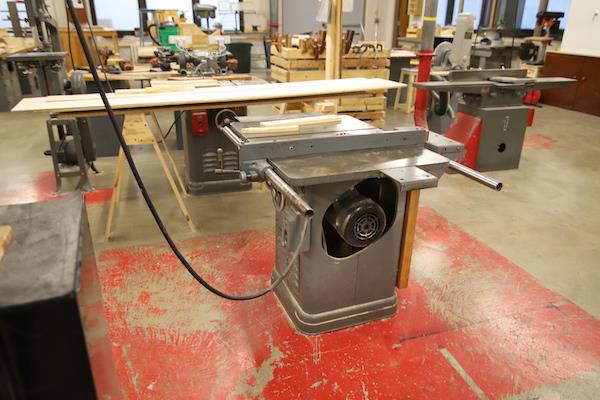 Shows a closeup view of a machine in front of a long table.